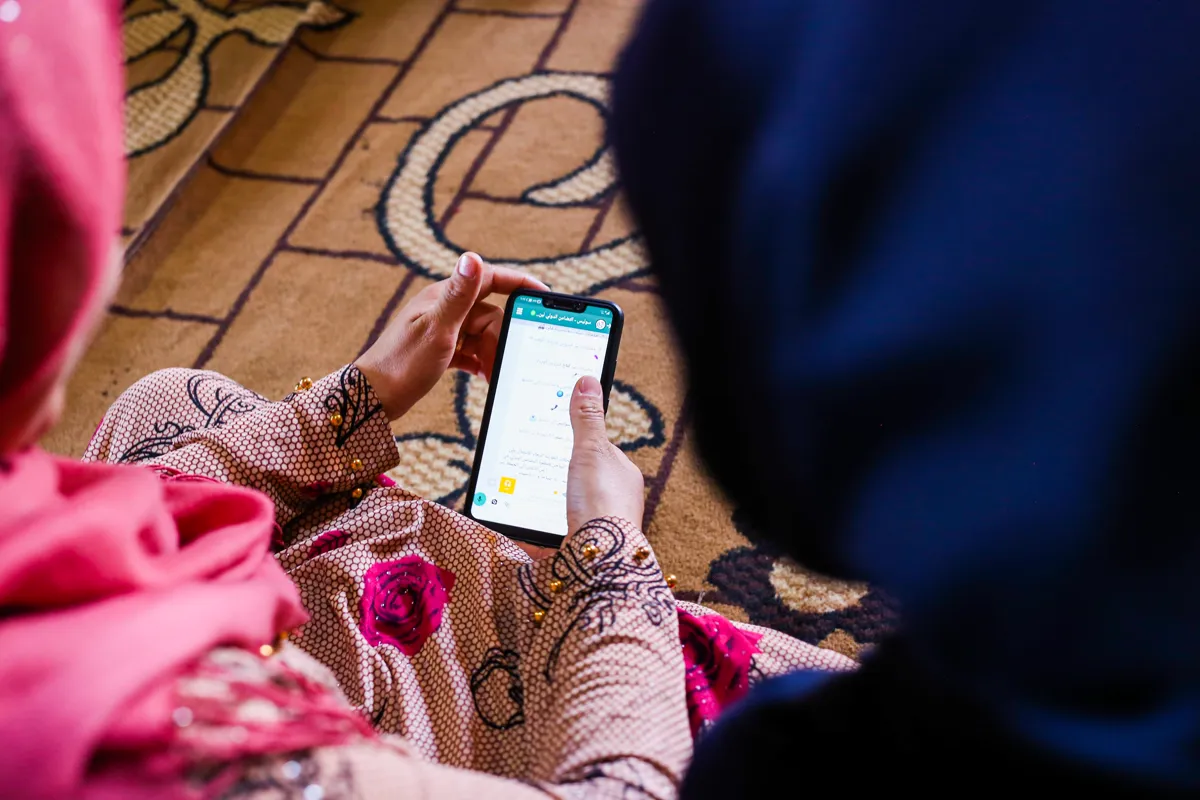 Deux femmes consultent le SOLIS bot sur WhatsApp depuis un téléphone mobile